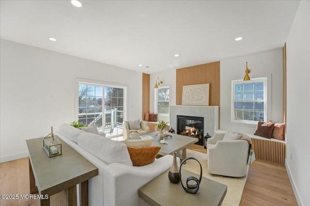 living room featuring a large fireplace, baseboards, light wood-style floors, and recessed lighting