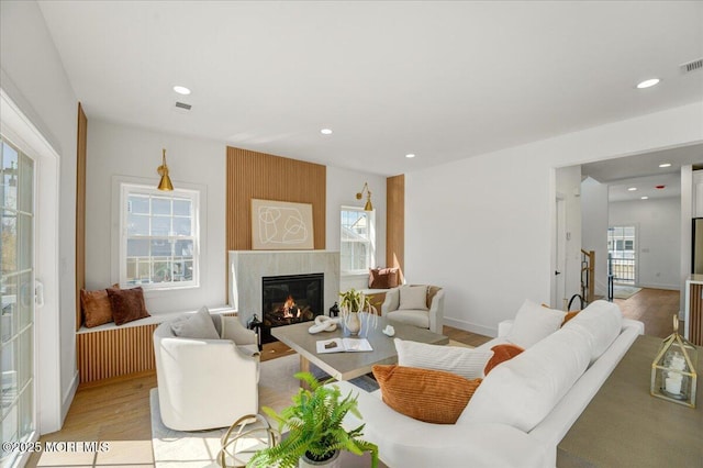 living area featuring a large fireplace, light wood-style flooring, recessed lighting, and a wealth of natural light