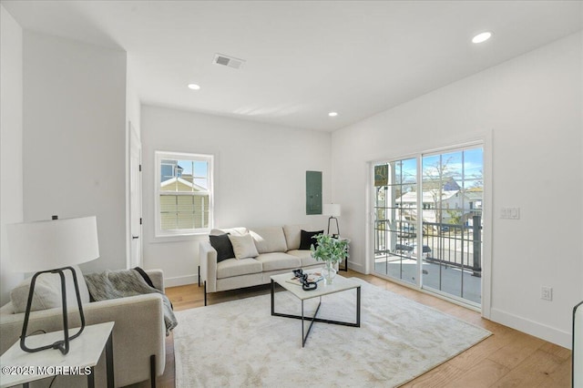 living room with baseboards, recessed lighting, light wood-style flooring, and electric panel