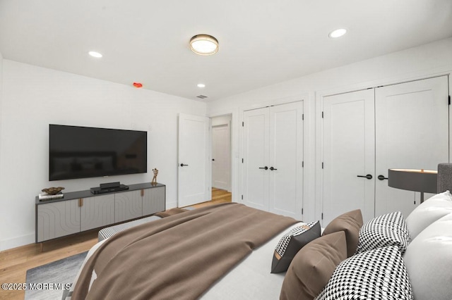 bedroom with recessed lighting, baseboards, multiple closets, and wood finished floors