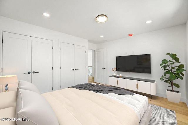 bedroom with light wood-style floors, multiple closets, and recessed lighting