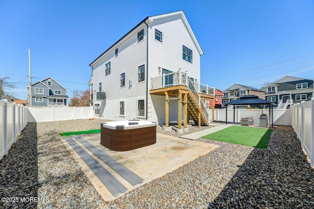 rear view of property featuring a patio, stairs, a fenced backyard, a gazebo, and a hot tub