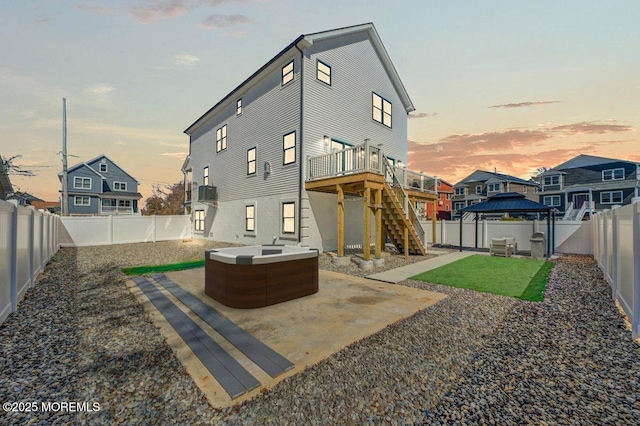 rear view of property with stairs, a patio area, a gazebo, a wooden deck, and a fenced backyard