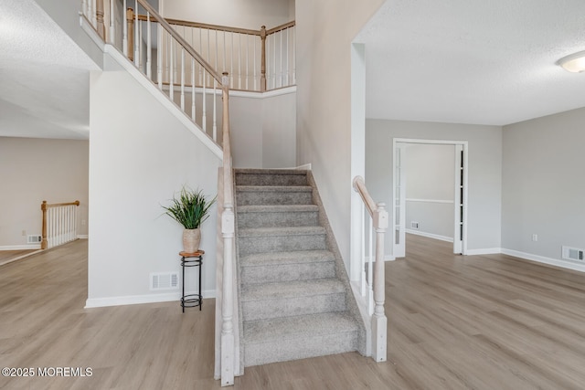 stairs featuring baseboards, visible vents, and wood finished floors