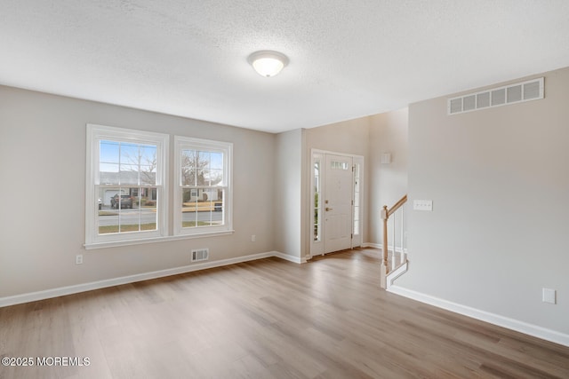 interior space featuring baseboards, visible vents, wood finished floors, and a textured ceiling