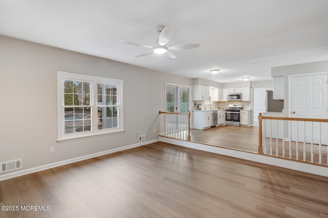 unfurnished living room featuring visible vents, light wood-style flooring, and a ceiling fan