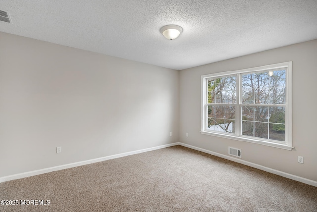 carpeted spare room with baseboards, visible vents, and a textured ceiling