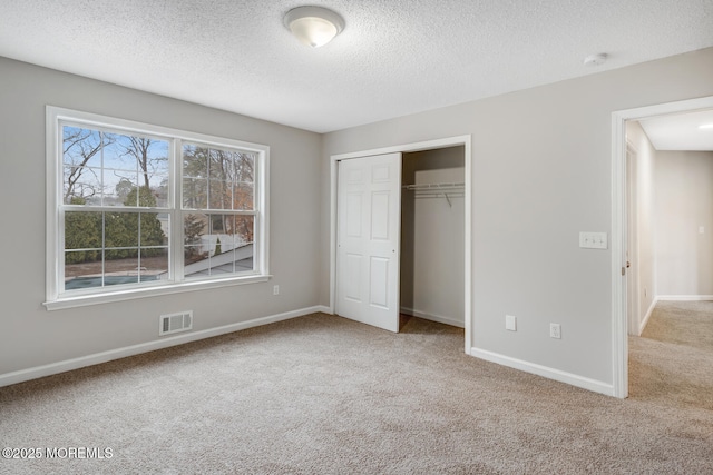 unfurnished bedroom with a closet, carpet floors, visible vents, and baseboards