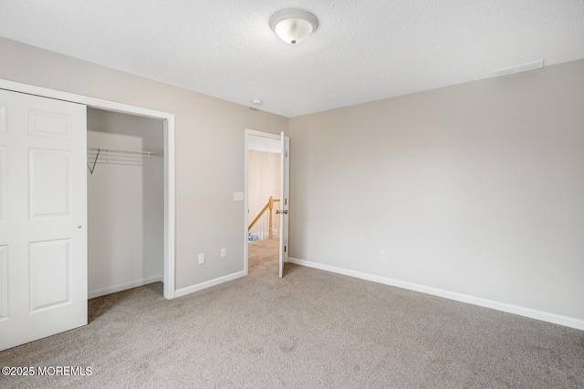 unfurnished bedroom featuring baseboards, carpet flooring, a textured ceiling, and a closet