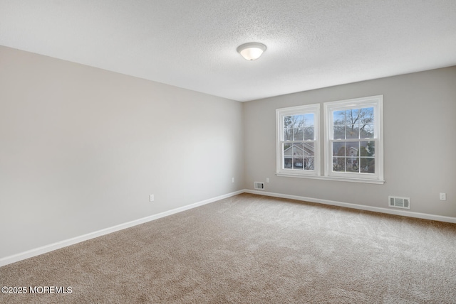 carpeted spare room featuring a textured ceiling, baseboards, and visible vents