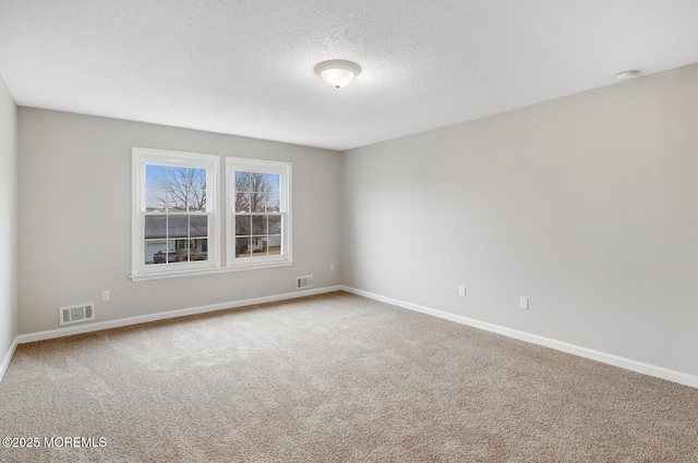 empty room featuring carpet floors, a textured ceiling, baseboards, and visible vents