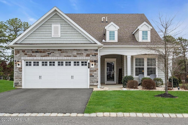 view of front of property featuring driveway, an attached garage, stone siding, and a front lawn