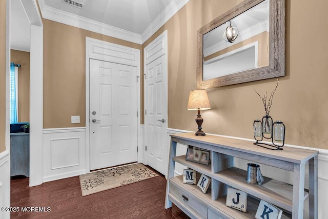 foyer entrance featuring a wainscoted wall, visible vents, crown molding, and dark wood-style flooring