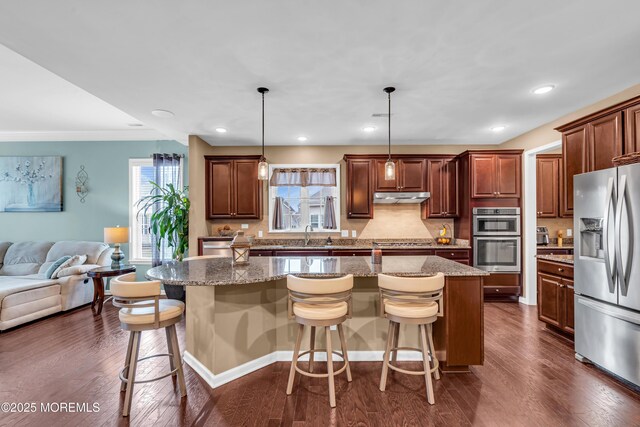 kitchen with open floor plan, under cabinet range hood, appliances with stainless steel finishes, and dark wood-style flooring