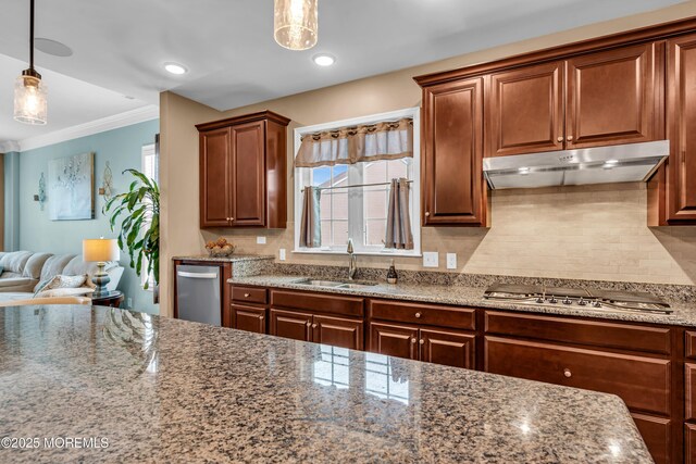 kitchen featuring stainless steel gas stovetop, tasteful backsplash, under cabinet range hood, a sink, and hanging light fixtures
