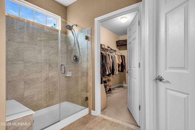 full bath featuring tile patterned floors, baseboards, a stall shower, and a spacious closet