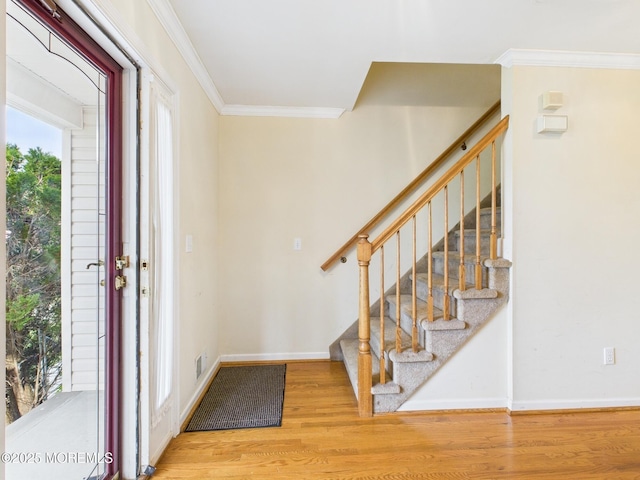 entryway with stairs, light wood finished floors, and crown molding