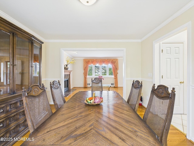 dining area featuring baseboards, ornamental molding, and a fireplace with flush hearth