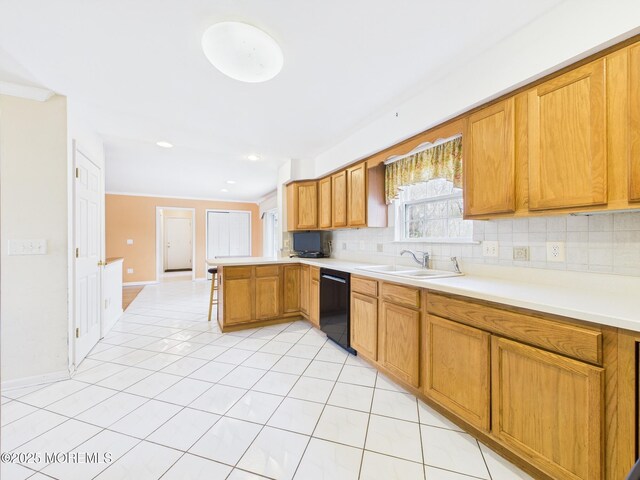kitchen with tasteful backsplash, light tile patterned floors, black dishwasher, a sink, and a peninsula