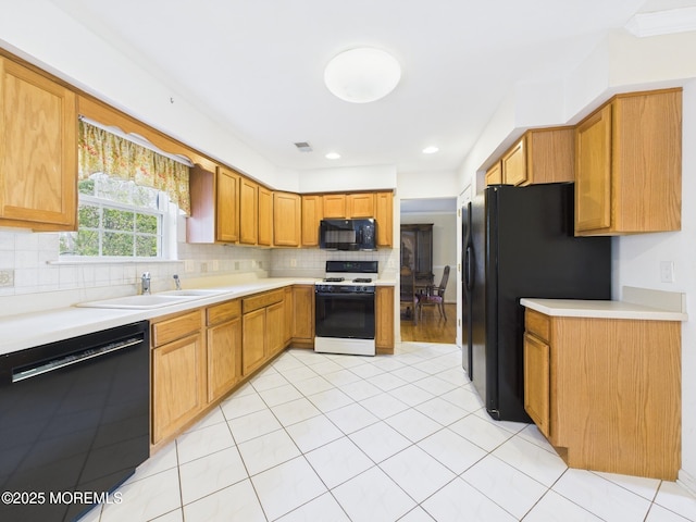 kitchen featuring black appliances, tasteful backsplash, light countertops, and a sink