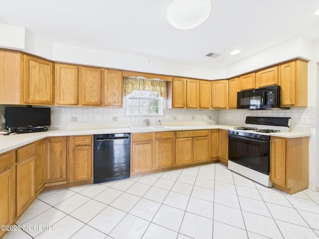 kitchen with a sink, black appliances, visible vents, backsplash, and light countertops