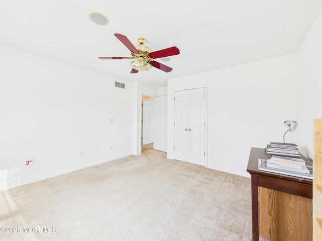 unfurnished bedroom with a closet, a ceiling fan, visible vents, baseboards, and light colored carpet