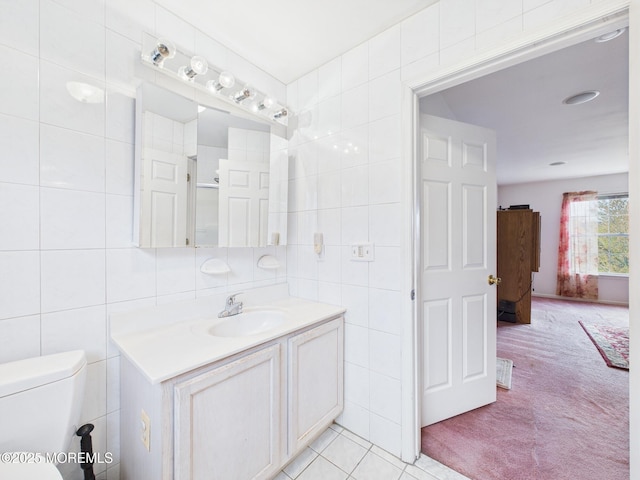 bathroom featuring toilet, tile patterned floors, tile walls, and vanity
