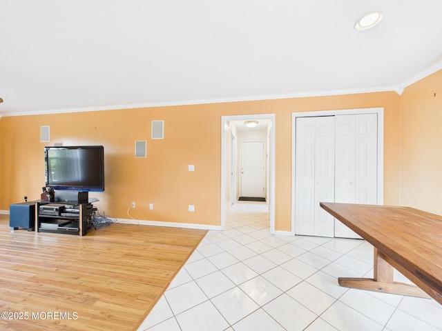 living room featuring baseboards, visible vents, light tile patterned floors, and crown molding