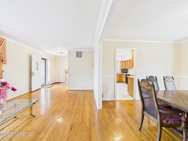 dining area with visible vents, light wood-type flooring, crown molding, and baseboards