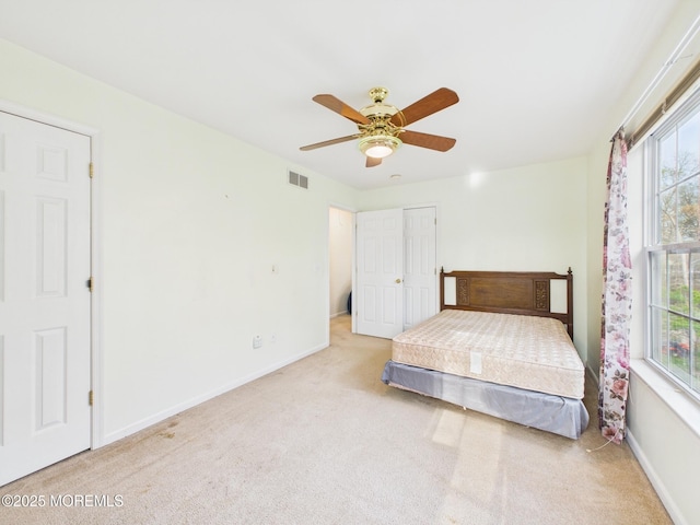 carpeted bedroom with visible vents, baseboards, a ceiling fan, and multiple windows