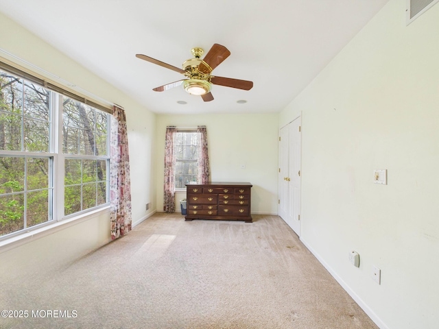 carpeted empty room featuring baseboards, visible vents, and ceiling fan
