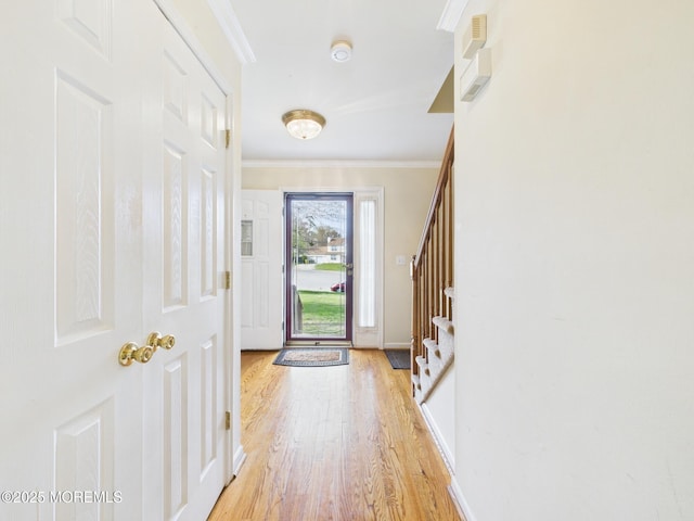 entrance foyer featuring baseboards, stairs, crown molding, and light wood-style flooring