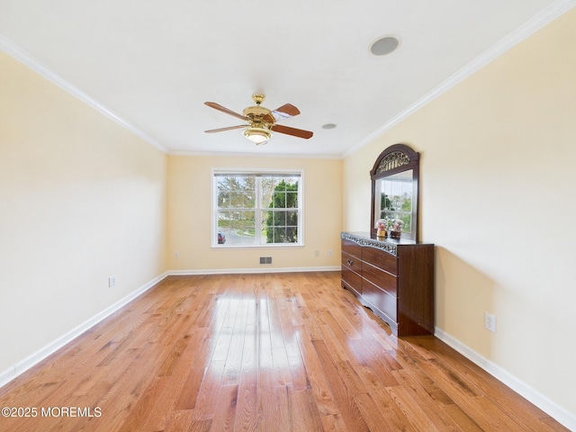 spare room with a ceiling fan, light wood finished floors, crown molding, and baseboards
