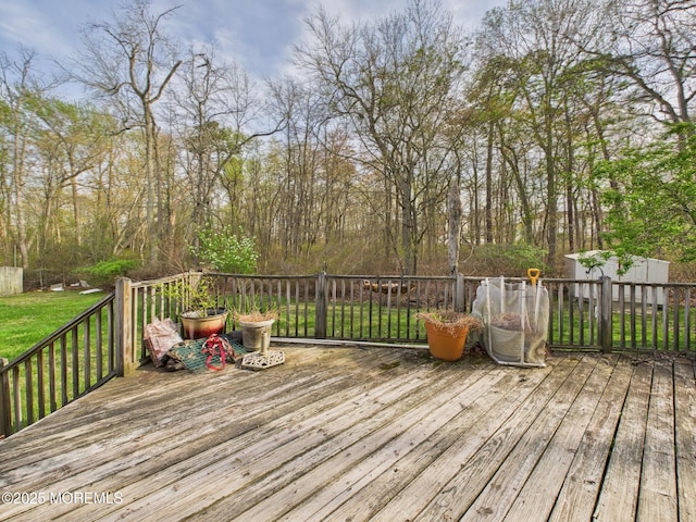 wooden terrace with a shed, an outbuilding, and a yard