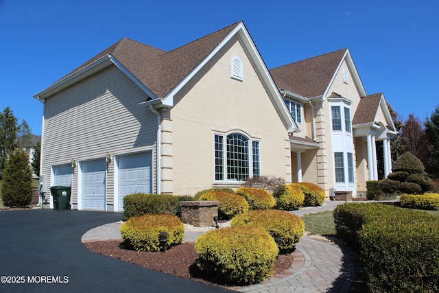 2 Lecarre Dr, Marlboro, NJ 07746 - view of side of property with a shingled roof, stucco siding, an attached garage, and aphalt driveway