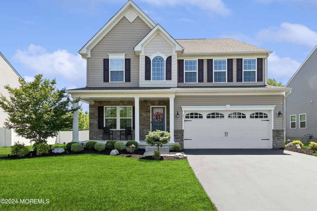 view of front of house with a garage, driveway, stone siding, and covered porch