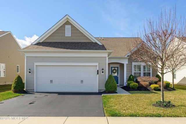 view of front of house with an attached garage, aphalt driveway, a front yard, and roof with shingles