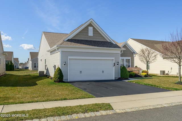 view of front of home featuring central air condition unit, roof with shingles, an attached garage, aphalt driveway, and a front lawn