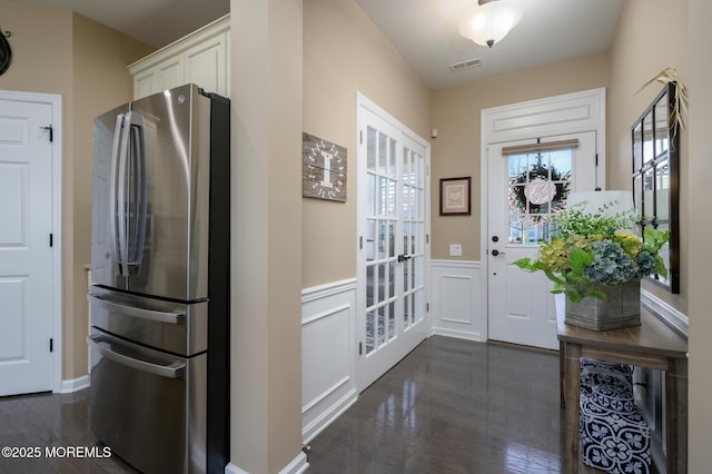 entryway featuring a wainscoted wall, visible vents, a decorative wall, and dark wood-style flooring