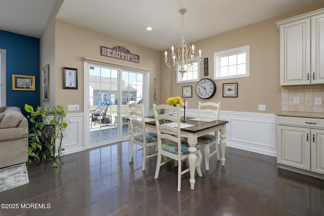 dining area featuring plenty of natural light, wainscoting, dark wood-type flooring, and an inviting chandelier