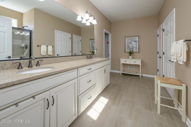 full bathroom with double vanity, a tile shower, baseboards, and a sink