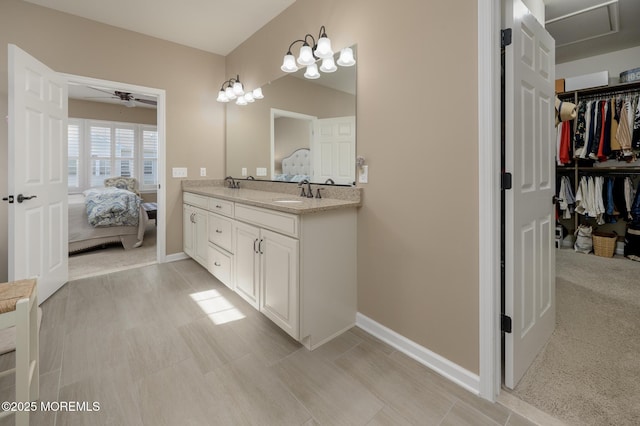 ensuite bathroom with a sink, a spacious closet, double vanity, and ensuite bathroom