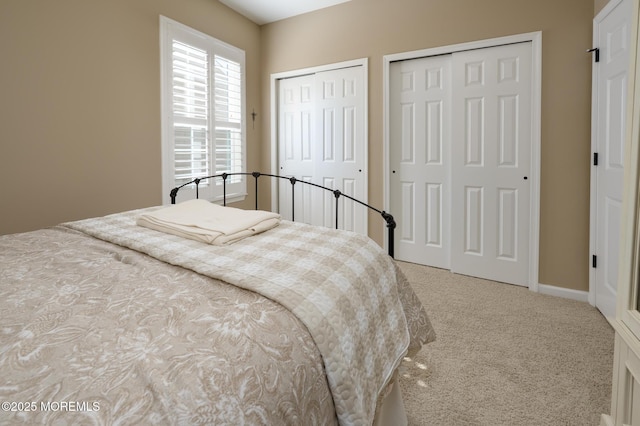 bedroom with baseboards, two closets, and carpet