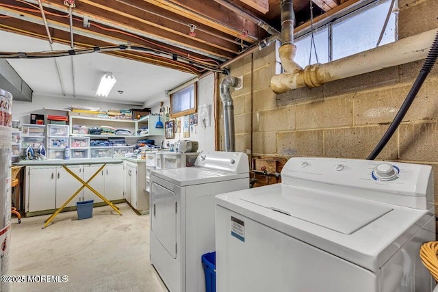 washroom featuring concrete block wall, laundry area, and washer and dryer
