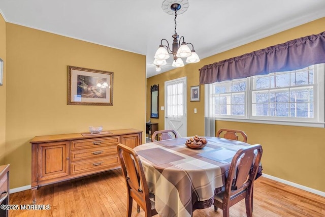 dining room with an inviting chandelier, baseboards, and light wood-type flooring