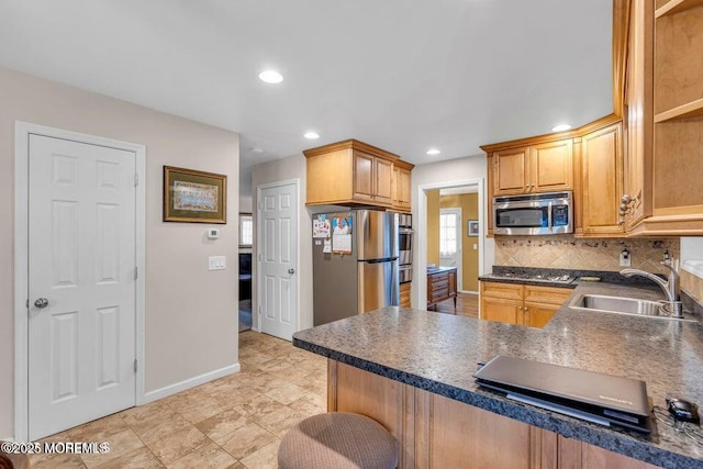 kitchen featuring a sink, backsplash, appliances with stainless steel finishes, a peninsula, and dark countertops