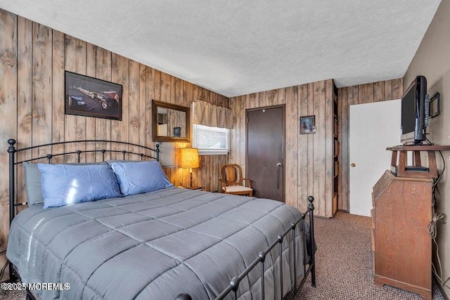 carpeted bedroom featuring a closet, wood walls, and a textured ceiling
