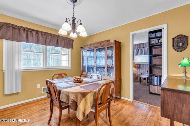 dining area with a notable chandelier, baseboards, and light wood finished floors