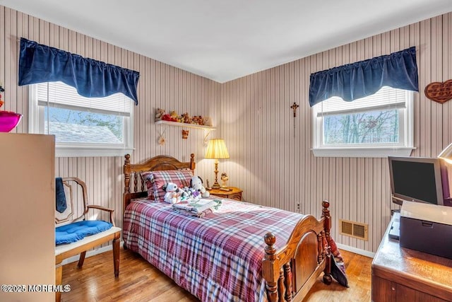 bedroom featuring wood finished floors, multiple windows, and visible vents
