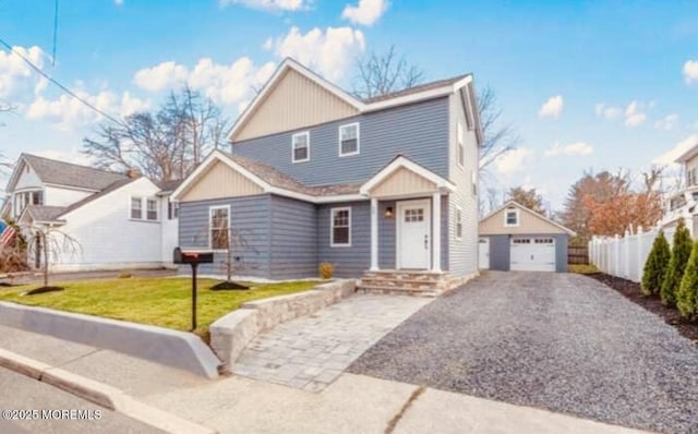 view of front facade with fence, driveway, a detached garage, and an outdoor structure